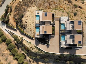 A modern multi-story building with a pool, a covered patio, and a landscaped area.