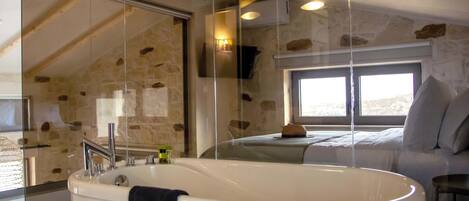Une salle de bain moderne avec une baignoire sur pieds, une douche à l’italienne et un mur en pierre.