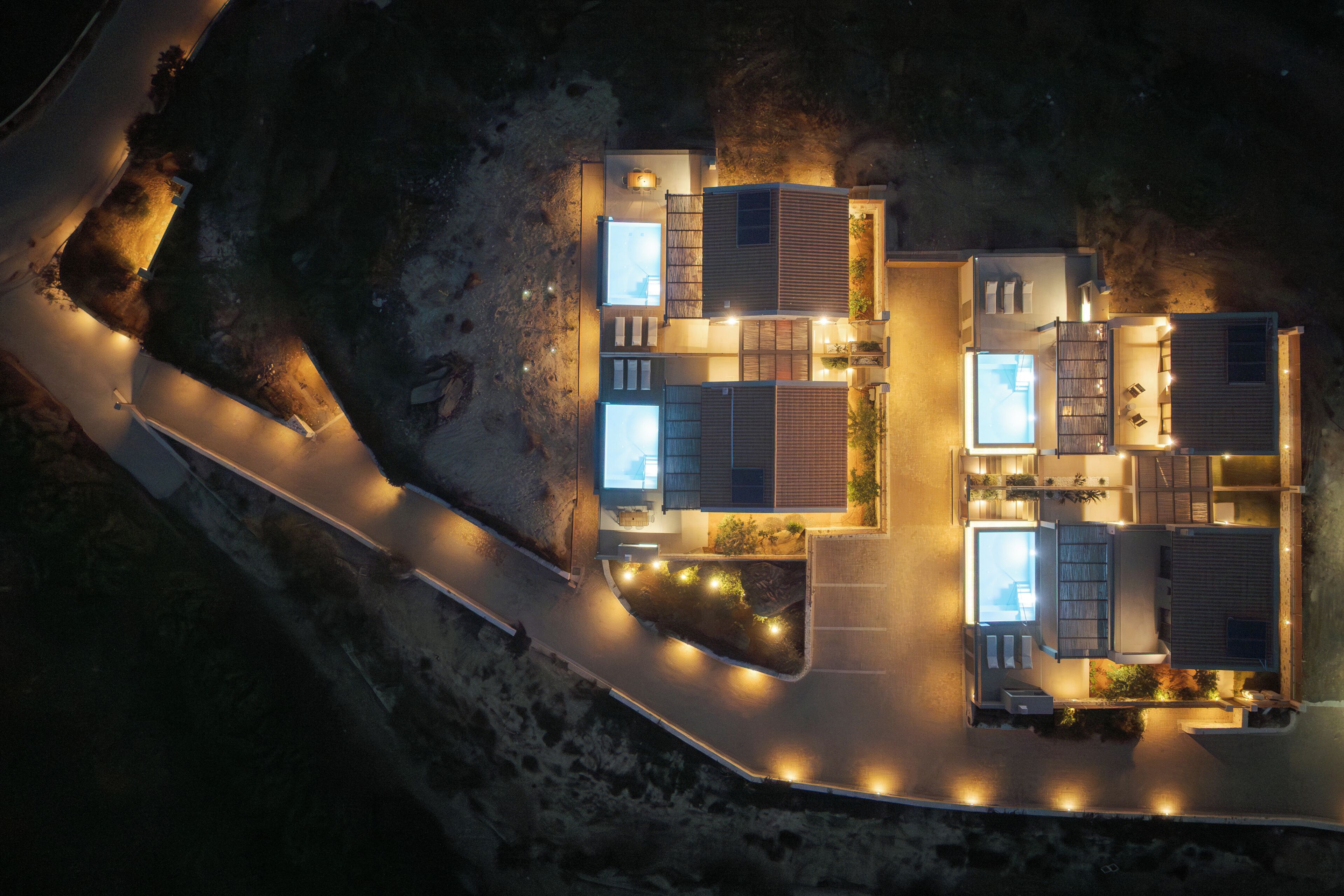 A modern house with multiple rooms, a driveway, and outdoor lighting.