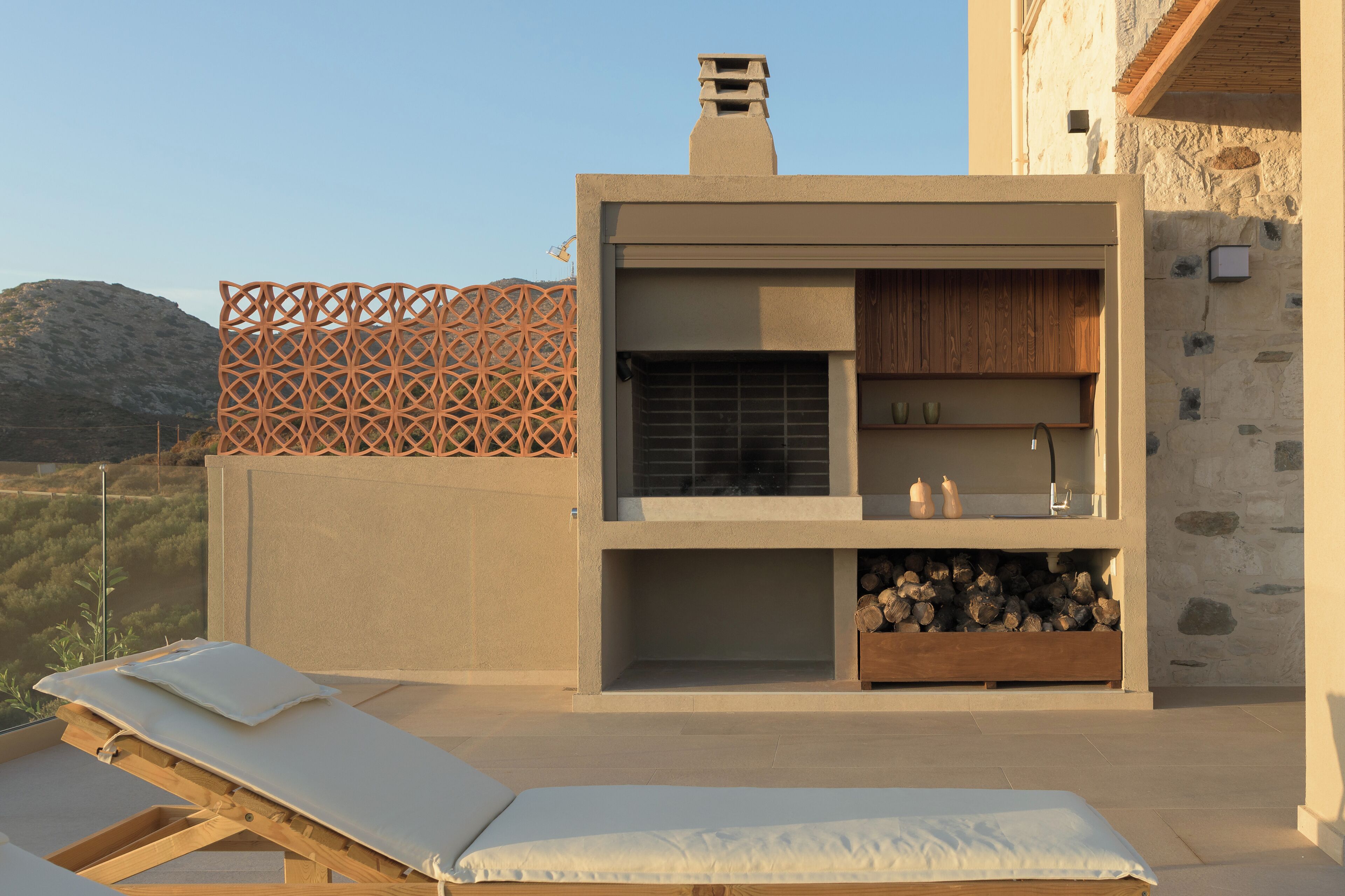 Un espace de détente extérieur moderne, doté d  ’une terrasse en bois, d’un coin salon intégré et d’un mur en pierre.