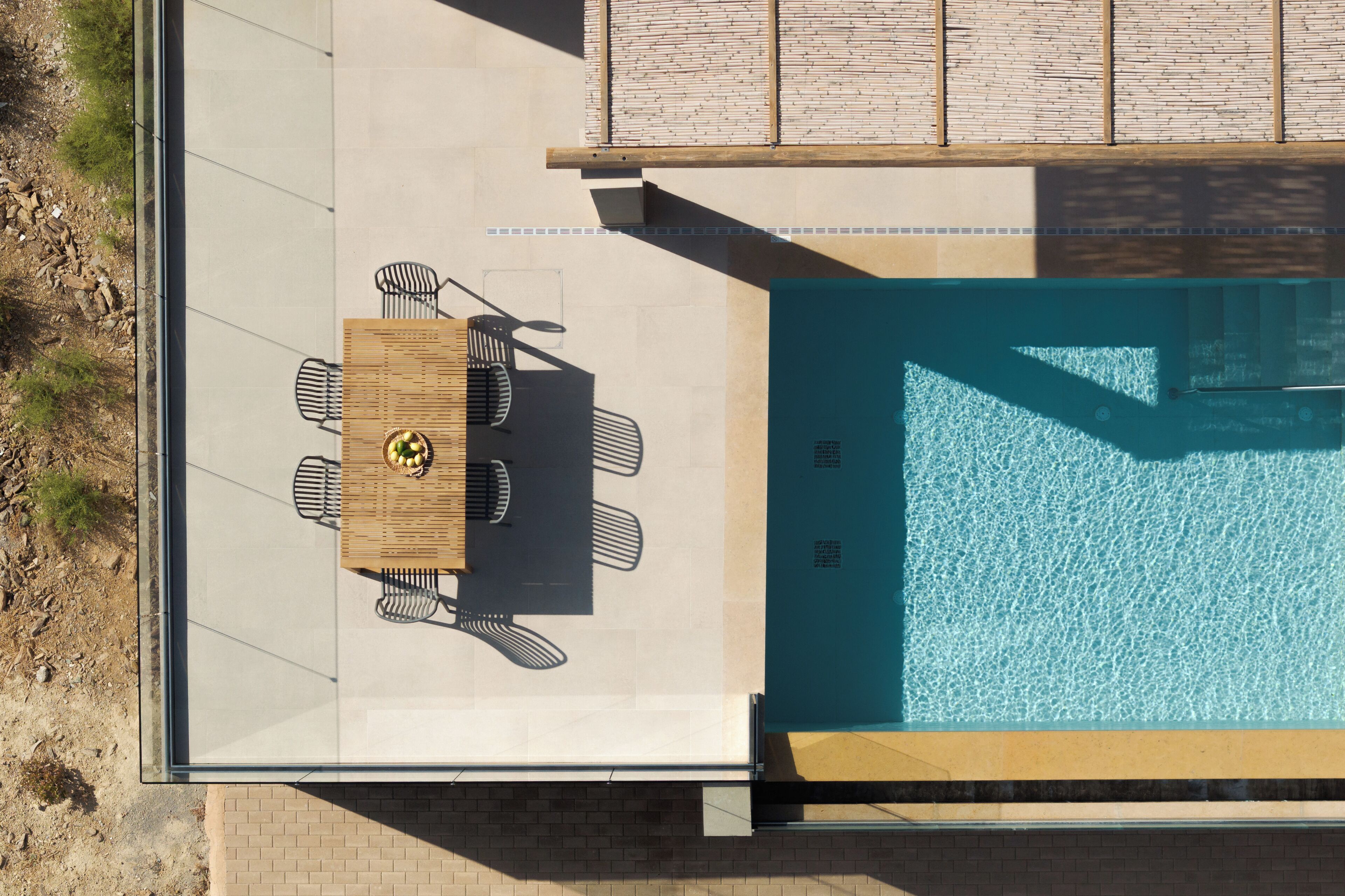 A rooftop pool with a table and chairs, surrounded by a patio area.