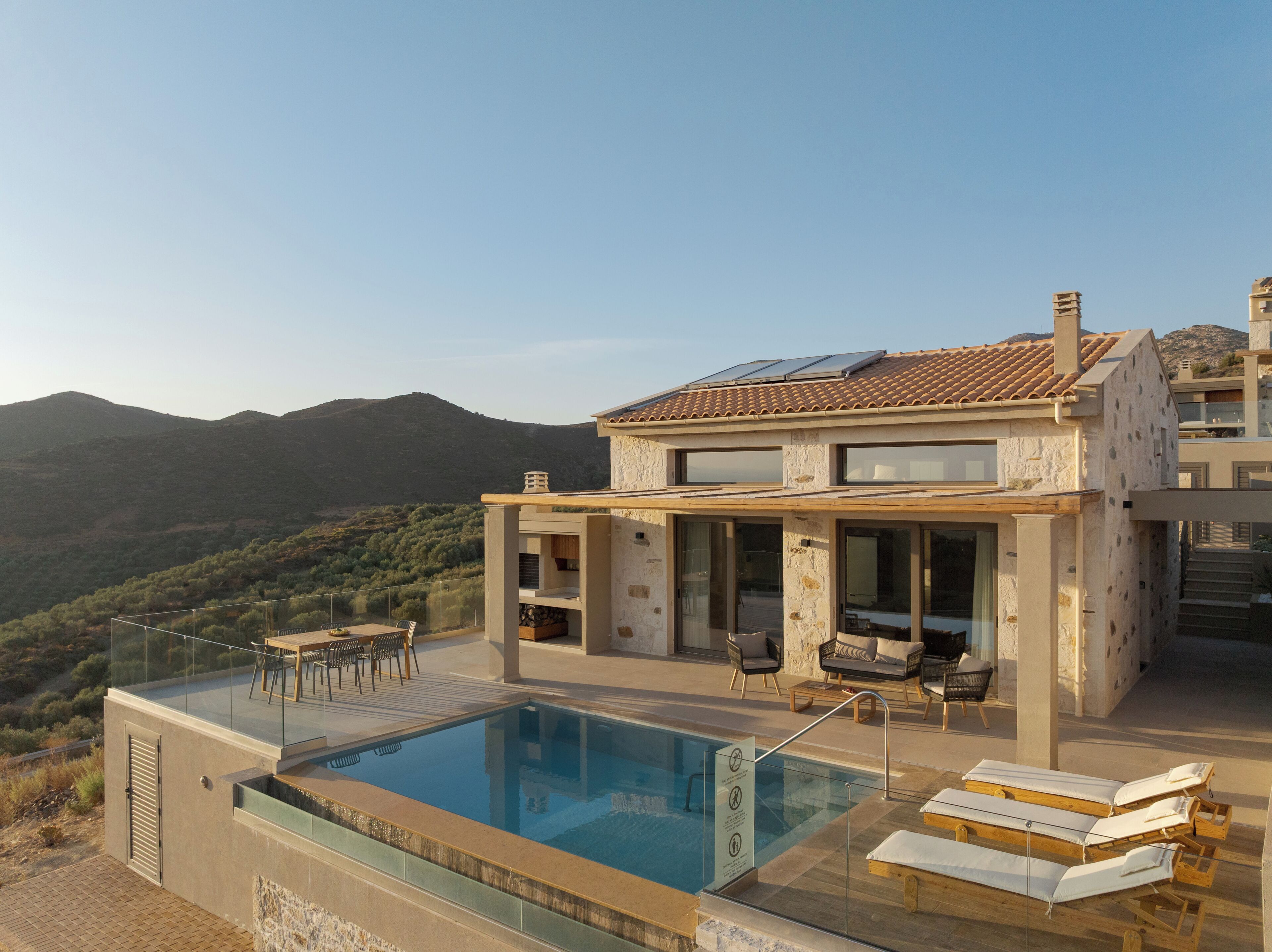 A modern house with a pool, outdoor seating, and a view of the mountains.