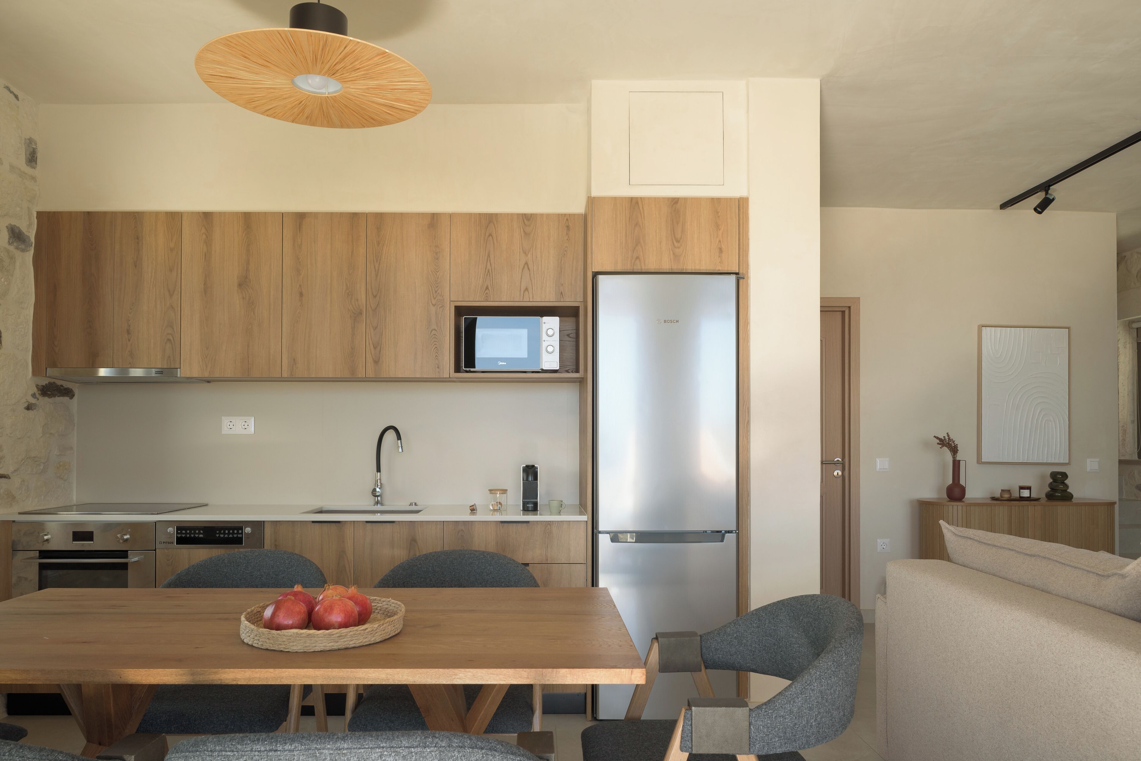 A modern kitchen with wooden cabinets, a Bosch refrigerator, a microwave, and a dining area with a table and chairs.