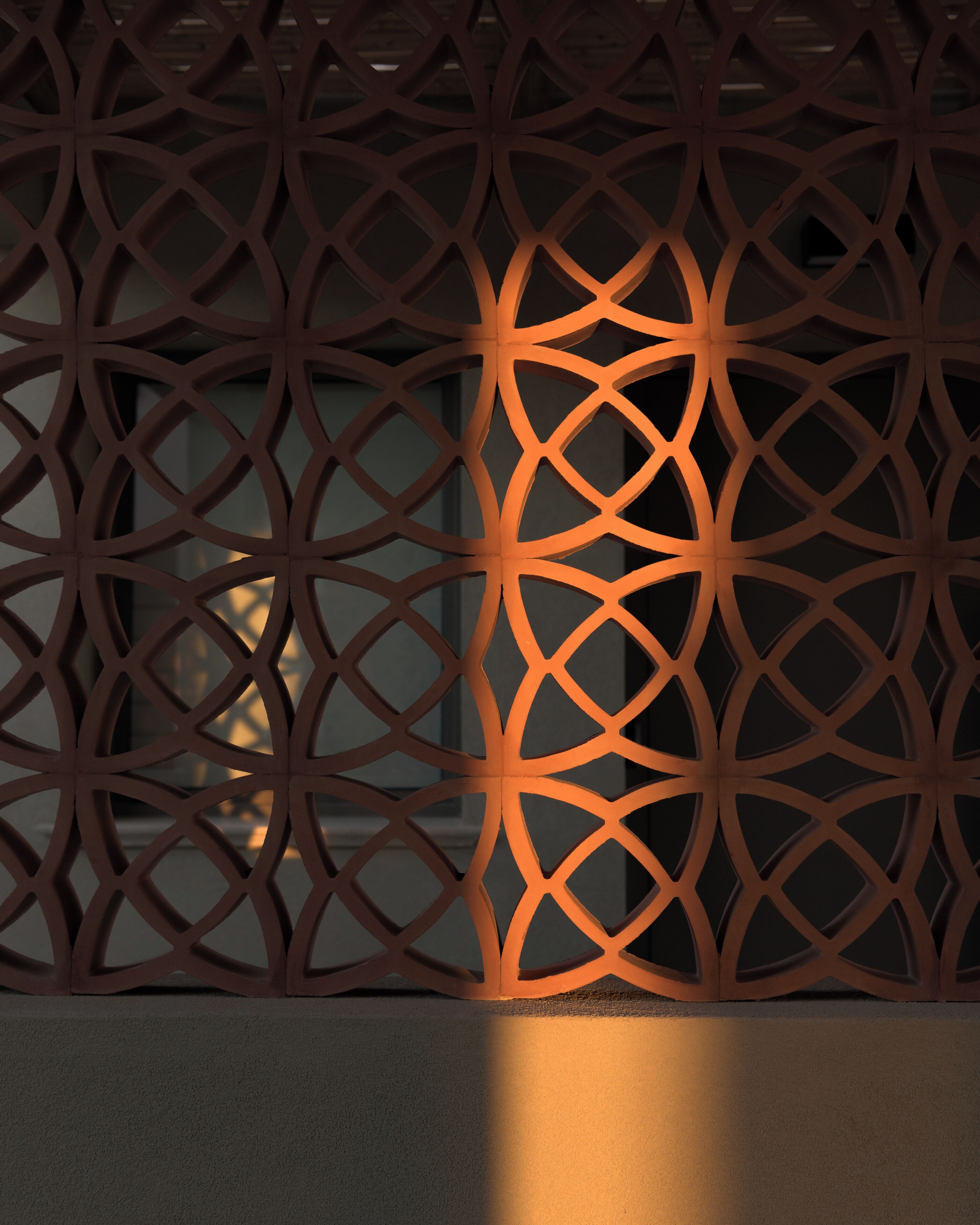 A geometric metal partition with a warm light source behind it.