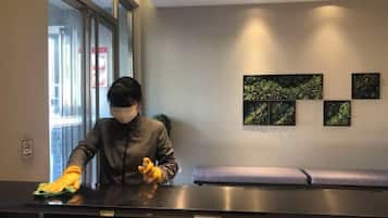 A person cleaning a reception desk in a hotel lobby with a bench and artwork on the wall.