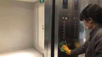 A person cleaning an elevator control panel.