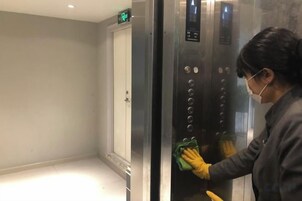Una persona limpiando el panel de control de un ascensor.