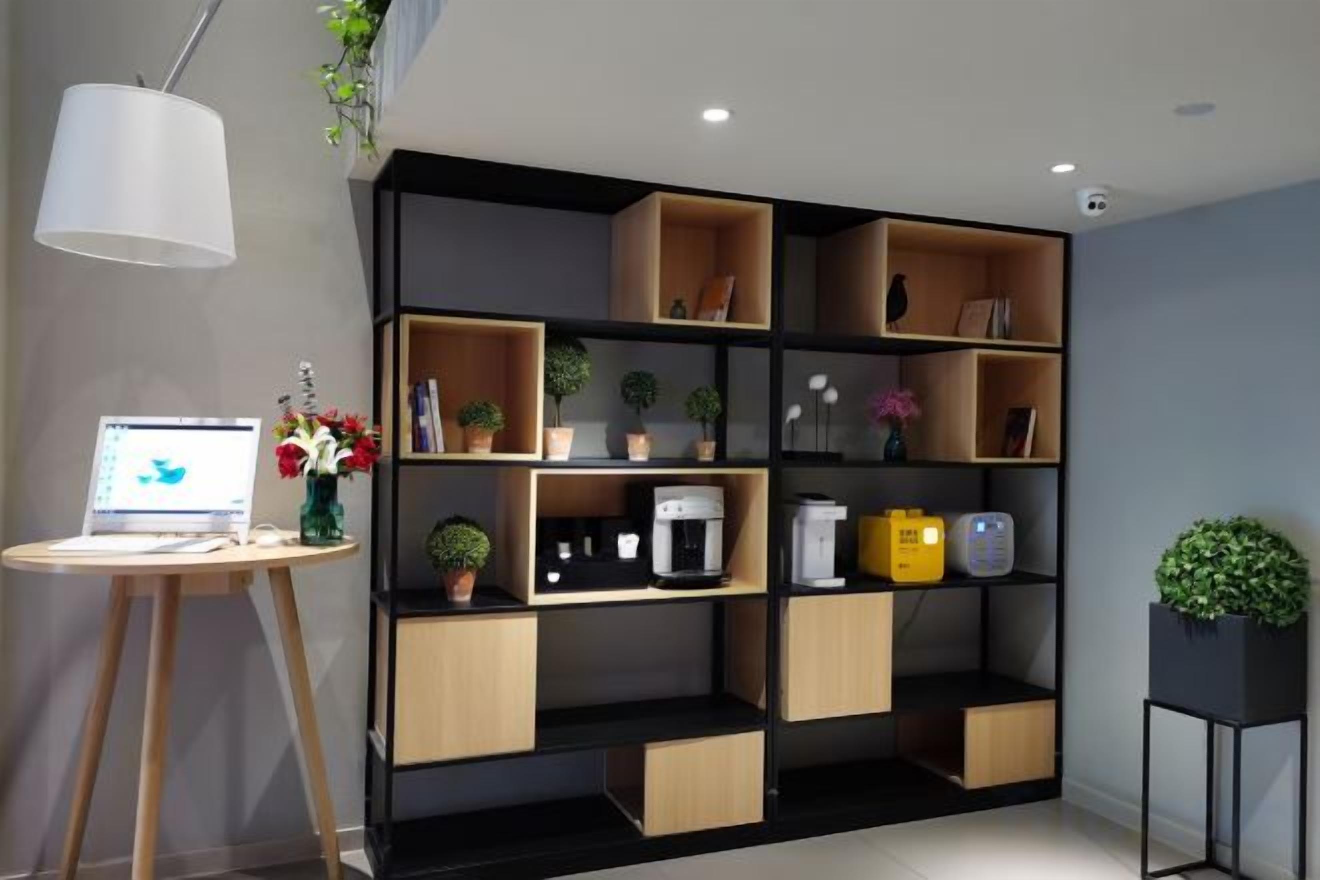 A modern room with a black and wooden shelving unit, a laptop on a desk, and a potted plant.