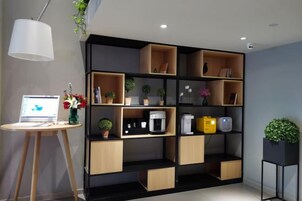 Una habitación moderna con una estantería negra y de madera, una computadora portátil sobre un escritorio y una planta en maceta.
