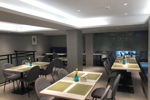 Un comedor moderno con varias mesas y sillas, una zona de bar y vistas a la ciudad.