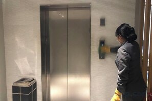 A person standing next to a metallic elevator in a room with a tiled wall. - Homeinn Ripple Yun Hotel (Shiyan Chezhan Road) (Shiyan)