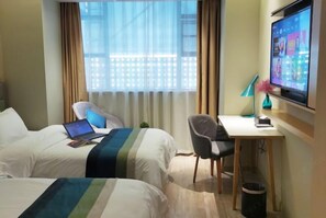 A hotel room with two beds, a desk, a chair, a TV, and a window with curtains.