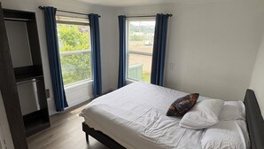 Une chambre à coucher avec un lit, une armoire et une fenêtre avec des rideaux.