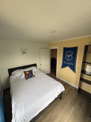 A bedroom with a bed, a door, a wall with a banner, and a hallway. - Hogwartz "House Ravenclaw" Themed 2-bd, 1-ba upstairs apartment. (Springfield)