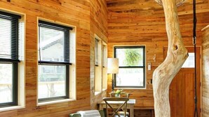 A cozy cabin interior with wooden walls, a dining area, and a unique tree stump feature. - Tuxedo Falls (Zirconia)