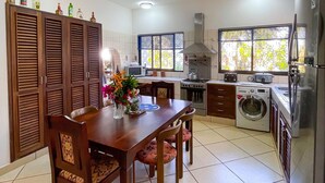 A modern kitchen with a dining area, featuring a wooden table, chairs, a ceiling fan, and built-in appliances. - Villa Sublime- Diani Beach 4 Bedrooms 50 meters from the beach- Luxurious🌴🔥⛱️ (Diani Beach)