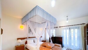 A bedroom with a four-poster bed, a nightstand, a dresser, and a large window with curtains. - Villa Sublime- Diani Beach 4 Bedrooms 50 meters from the beach- Luxurious🌴🔥⛱️ (Diani Beach)