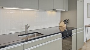 A modern kitchen with a stainless steel sink, a built-in oven, and a knife block. - Amazing 1BR flat in the city centre (West 8) (Zürich)