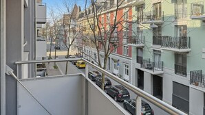 A multi-story residential building with balconies, a parking area with cars, and a clear sky. - Amazing 1BR flat in the city centre (West 8) (Zürich)
