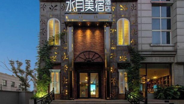 A hotel entrance with a dark facade, illuminated by vertical lights, and a central archway. - Shuiyue Qinghua Hotel (Deqing)