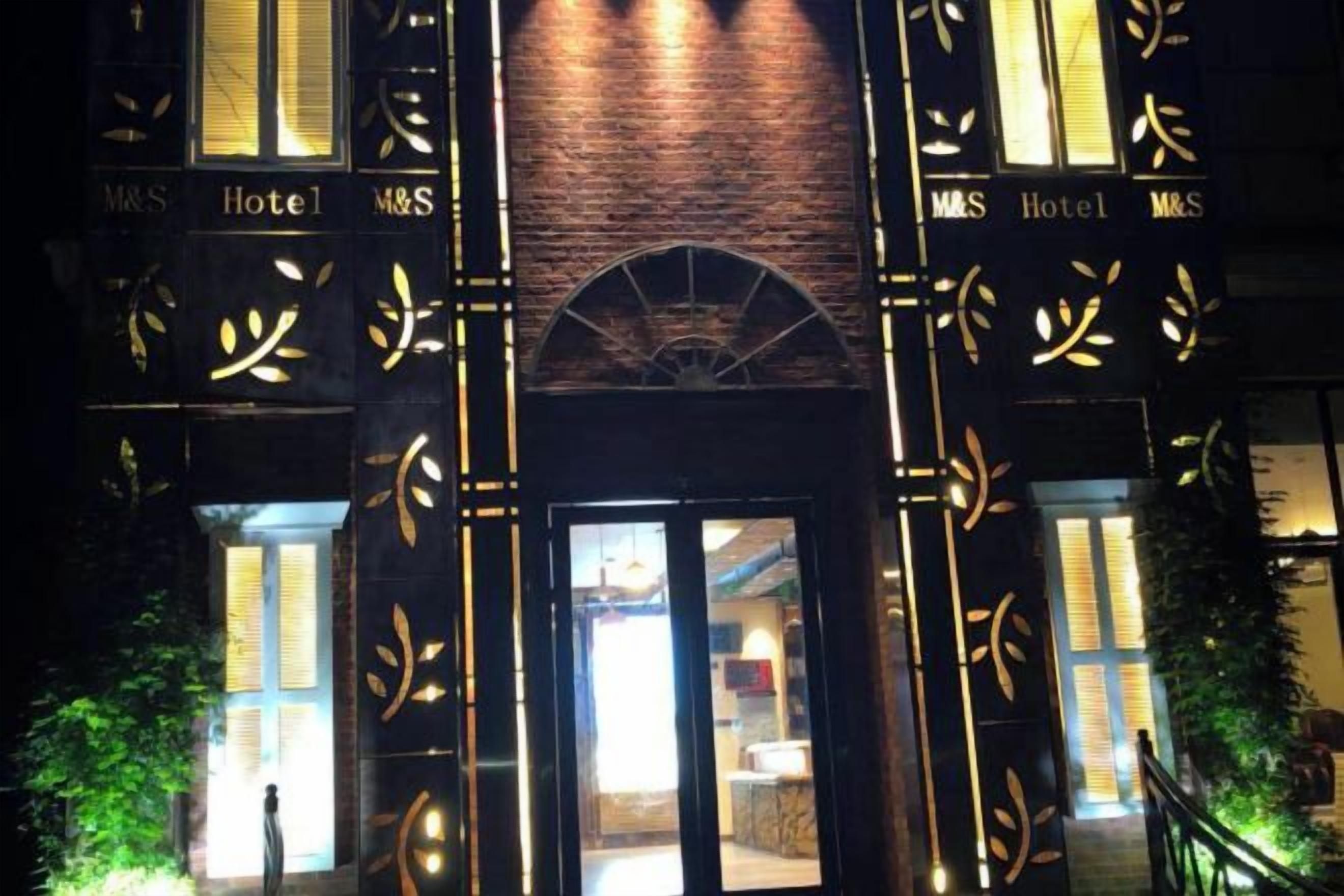 A hotel entrance with a brick facade and illuminated signage.