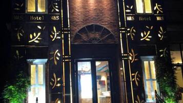 A hotel entrance with a brick facade and illuminated signage.