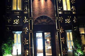 A hotel entrance with a brick facade and illuminated signage. - Shuiyue Qinghua Hotel (Deqing)