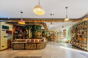 A hotel lobby with a reception desk, bookshelves, and hanging pendant lights. - Shuiyue Qinghua Hotel (Deqing)