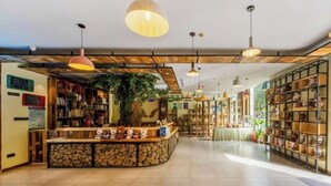 A bookstore with a central counter, shelves on both sides, and hanging pendant lights. - Shuiyue Qinghua Hotel (Deqing)