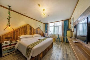 A bedroom with a wooden headboard, a bed with white linens, a hanging light fixture, a round chair, a small table, and a TV on the wall. - Shuiyue Qinghua Hotel (Deqing)