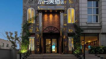 A hotel entrance with a brick facade, large arched doorway, and illuminated signage.