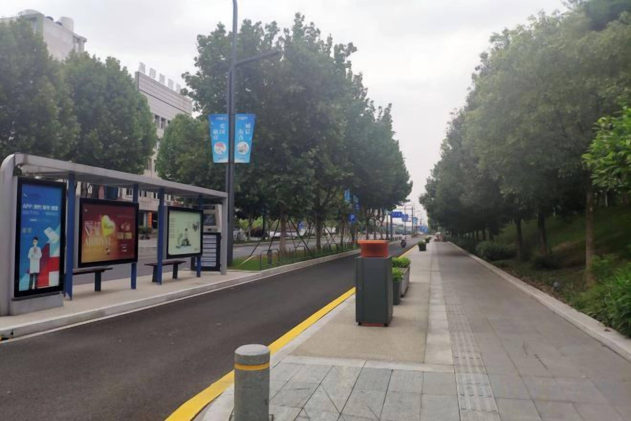 A sidewalk with a bus stop and advertisements.
