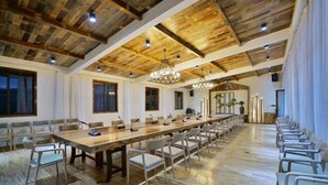 A large conference room with a long wooden table, multiple chairs, and a high ceiling with exposed beams. - Shuiyue Qinghua Hotel (Deqing)