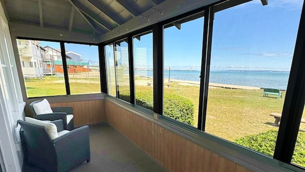 A covered outdoor seating area with a view of the beach and ocean. - Lake Cottage at Beachcomber of Mackinaw (Mackinaw City)