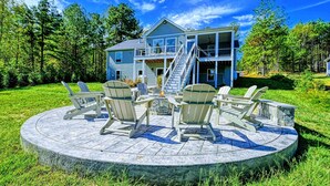 Un bâtiment à deux étages doté d’un balcon, entouré d’une pelouse où sont disposées des chaises Adirondack.