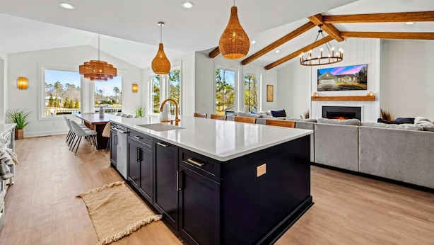 Une cuisine moderne dotée d’un grand îlot central, de luminaires suspendus et d’une cheminée.