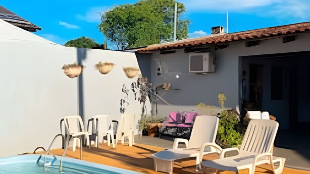 Una piscina con sillas de descanso, un área de patio y un edificio con techo de tejas.