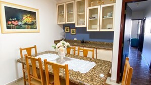 Un comedor con mesa de granito, sillas de madera y un cuadro en la pared.