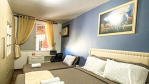 Habitación de hotel con una cama grande, un escritorio, una silla y una ventana con cortinas.