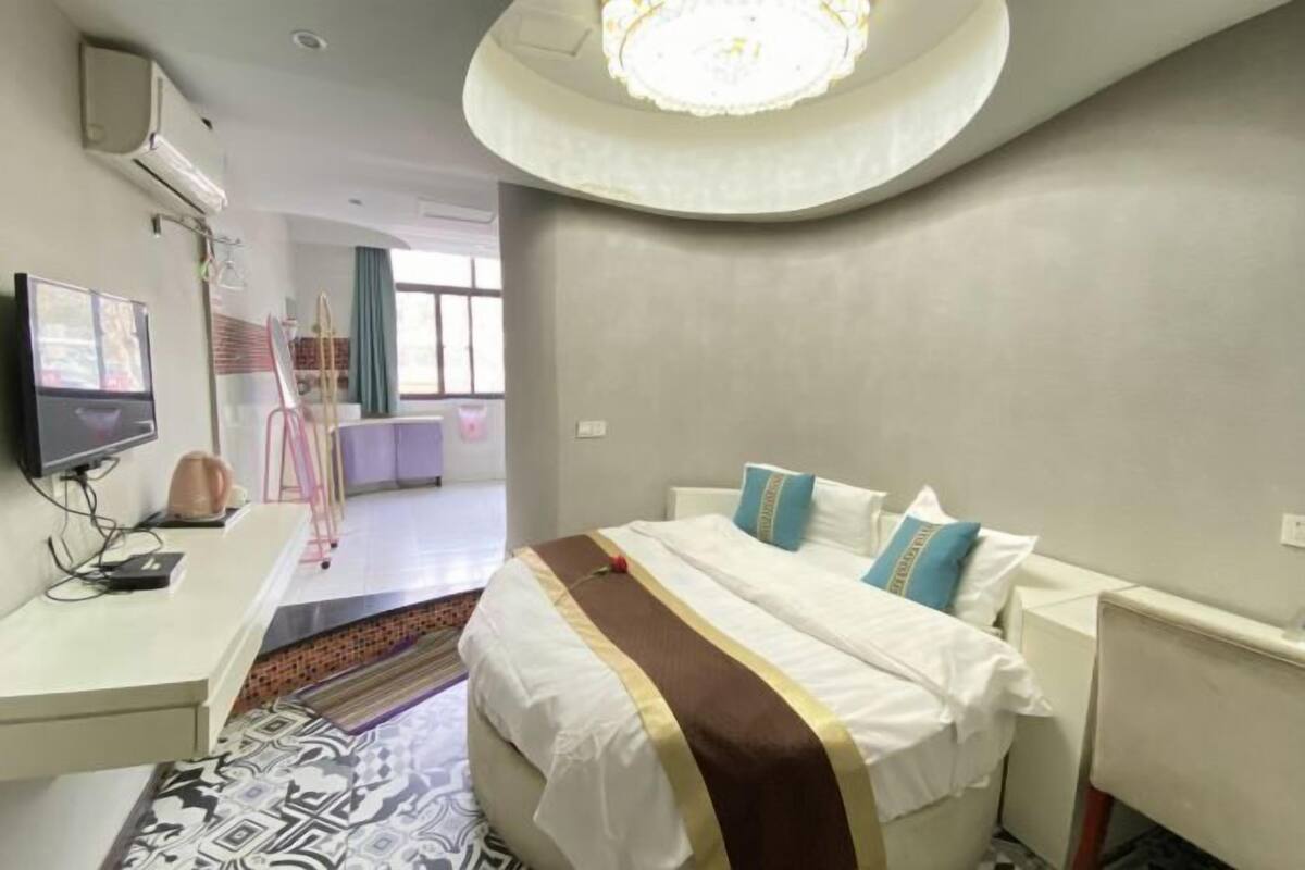 Une chambre d’hôtel avec un lit, un bureau, une télévision et une grande fenêtre.