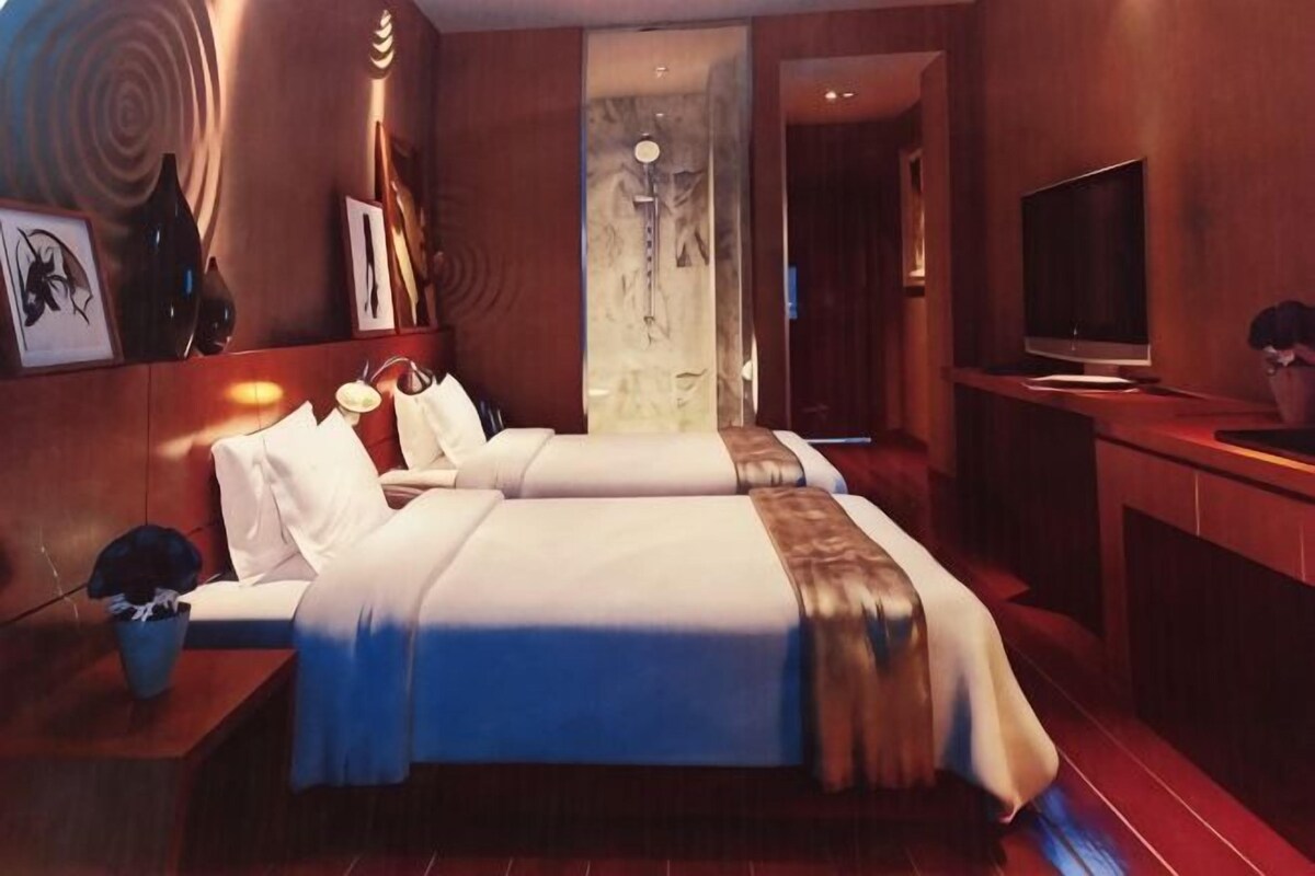 Una camera d'albergo con due letti, televisione e bagno.