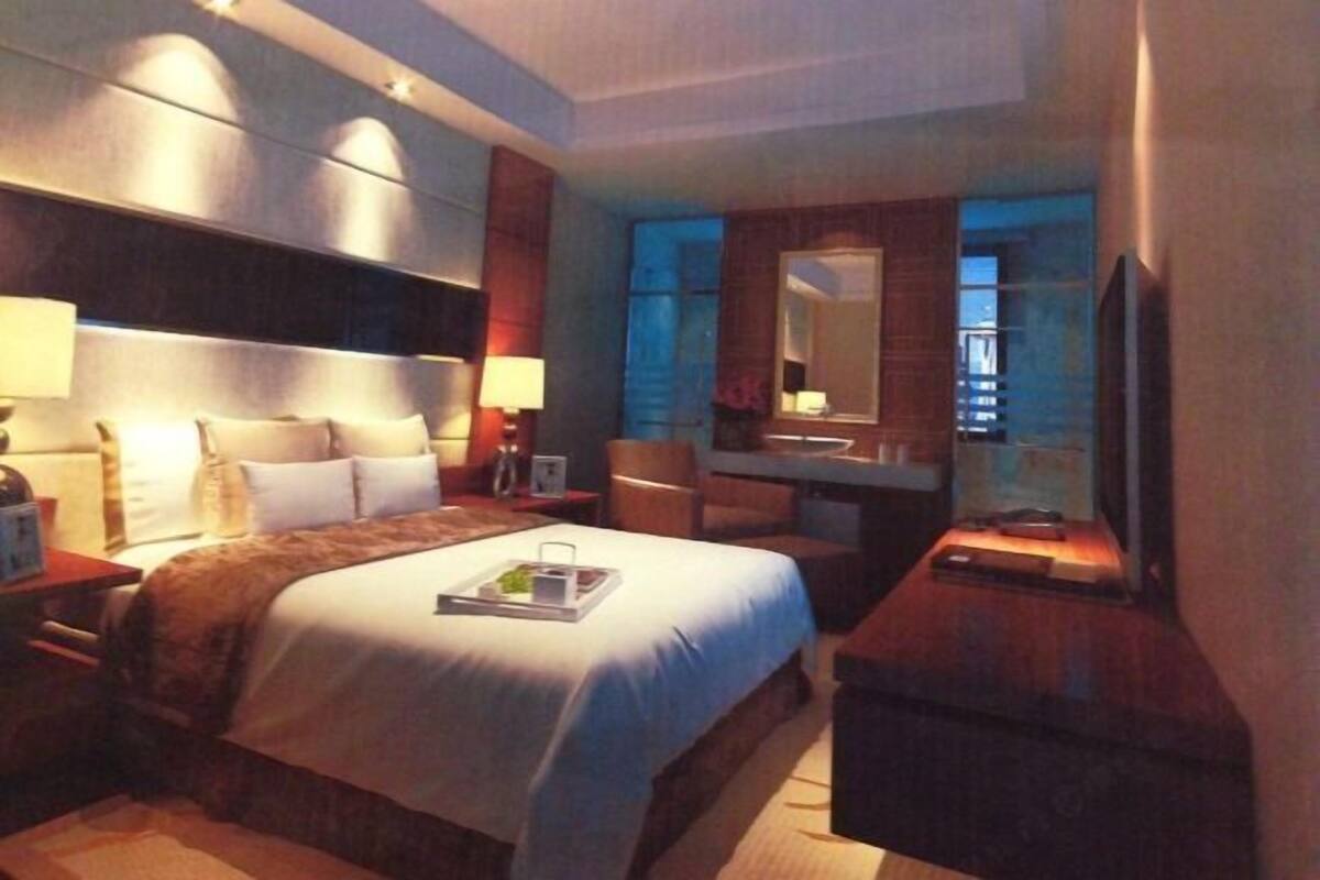 Une chambre d’hôtel avec un grand lit, un bureau, une chaise, un miroir et une télévision.