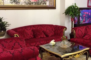 Un sofá rojo con una mesa de centro de vidrio en una habitación con una planta en maceta y un cuadro en la pared.