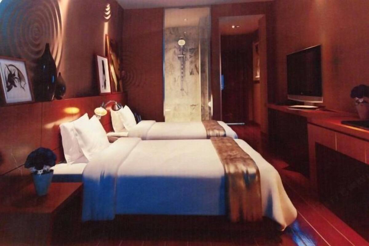 Une chambre d’hôtel comprenant un lit, des tables de chevet, un téléviseur et une œuvre d’art accrochée au mur.