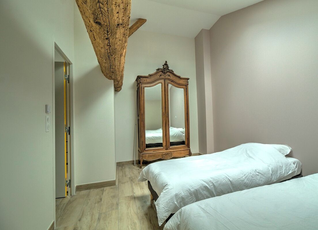 Ein Schlafzimmer mit zwei Betten, einem Holzschrank und einem Holzbalken an der Decke.