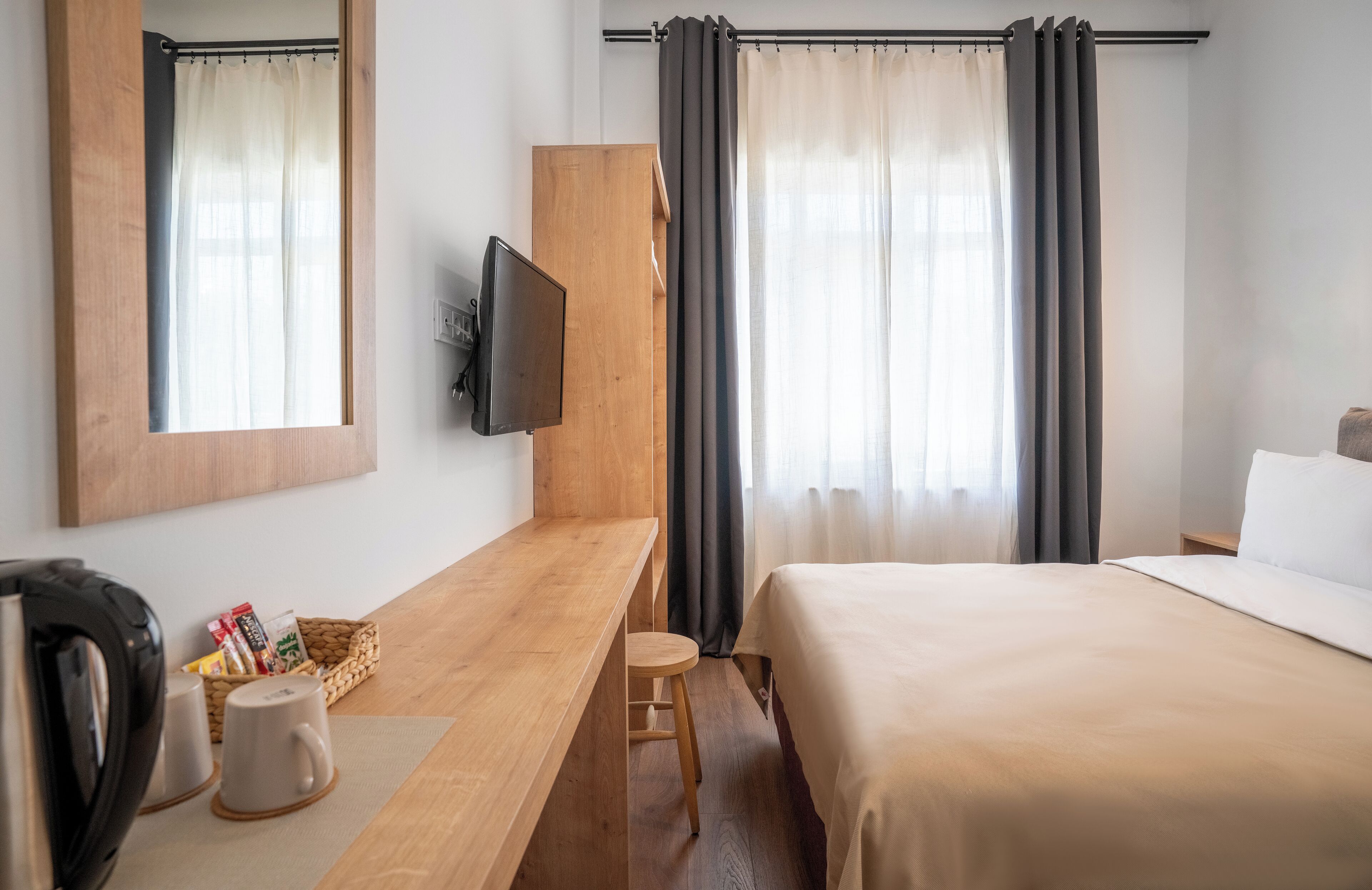 Une chambre d’hôtel avec un bureau en bois, une télévision, un lit et des rideaux.