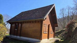 A small wooden cabin with a sloped roof, a front door, and a window. - AU DEPART DE MULTIPLES RANDONNEES (Murol)