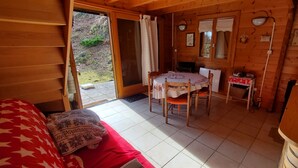 A cozy cabin interior with a dining area, a kitchen, and a living space. - AU DEPART DE MULTIPLES RANDONNEES (Murol)