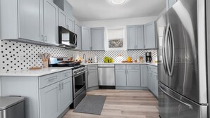 Una cocina moderna con armarios grises, electrodomésticos de acero inoxidable y suelo de madera.