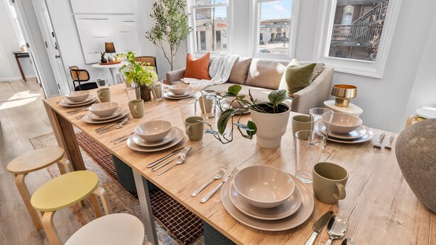 Un comedor con una mesa de madera dispuesta para cuatro personas, rodeado de sillas.